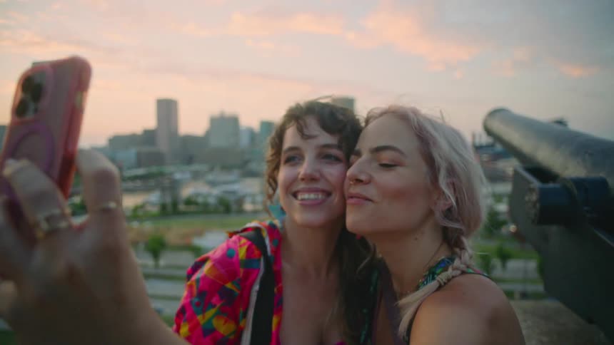 Two friends take a selfie next to a cannon in a park at sunset
