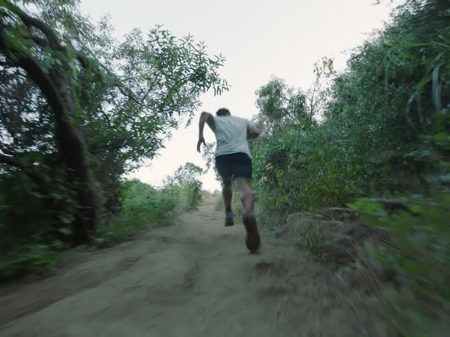 A man runs up a hillside trail on a summer day