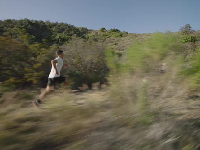 Man running through the hills in an environment surrounded by vegetation