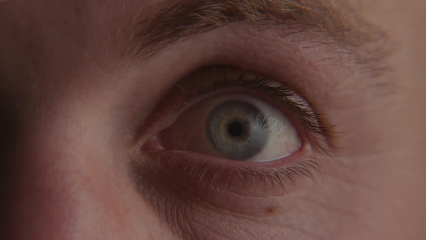 Extreme close up of a mans eye that is closed and opens