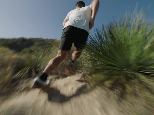 A white man runs up a dirt path in nature