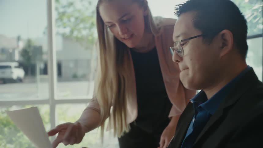 Colleague discusses paperwork to another in the office