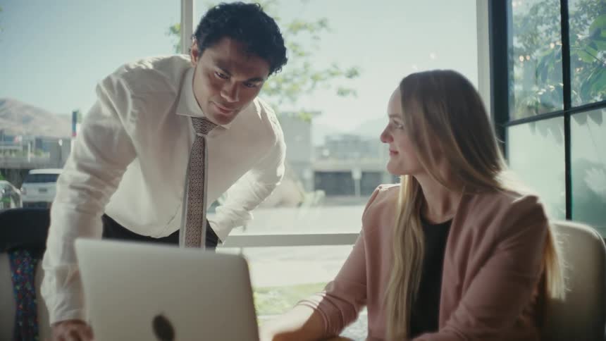 Two coworkers working at the office acknowledge each other with a nod