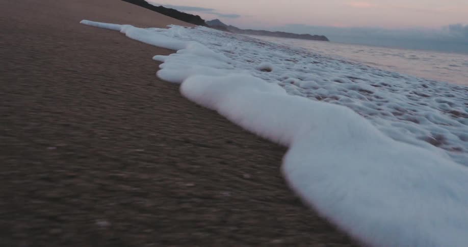 Soft foamy waves hitting the beach sand one morning