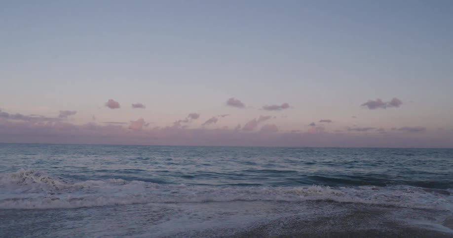 Surf foams on the beach under a red tinted sky