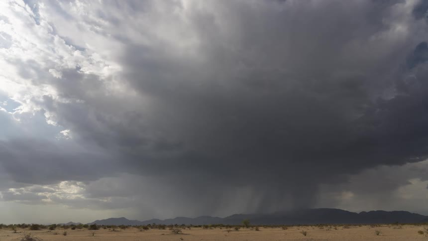 Vast desert landscape under a dramatic sky with dark clouds from an approaching storm