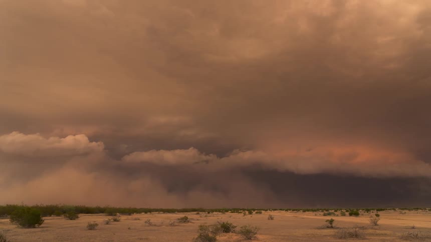Storm clouds move over a desert at dusk