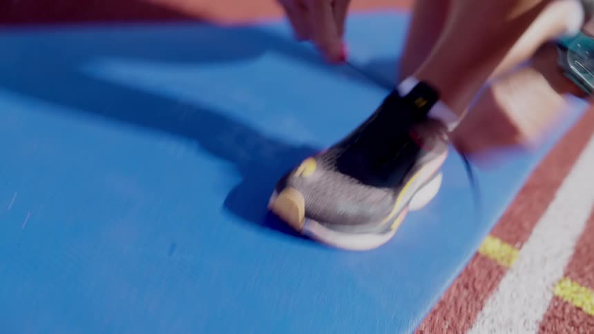 Close up of a mans hands tying the laces of a running shoe on a track