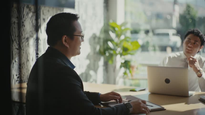 Two men talk at the desk