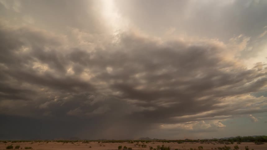 A vast desert landscape under a dramatic sky rain falling from storm clouds