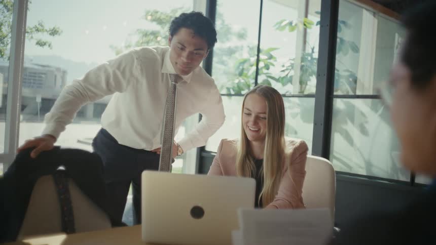 Two cheerful men and a woman talking at an office table