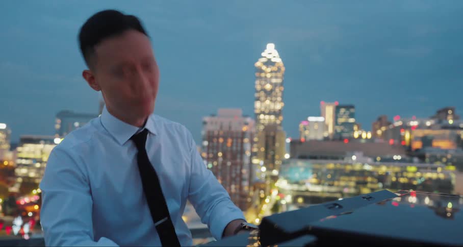 Man playing the piano on the terrace of a building and in the background a metropolis illuminated at night