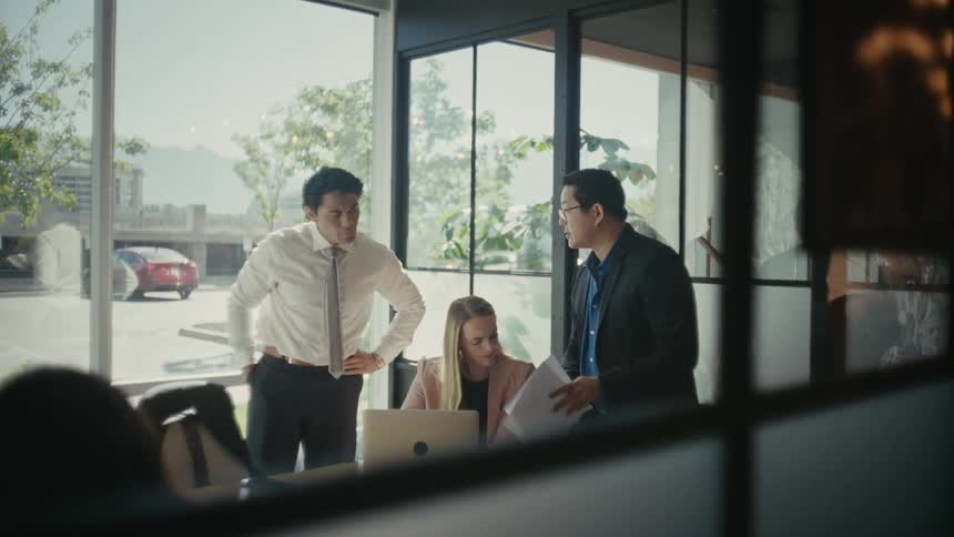 Woman sitting and two other men next to her in an office environment talking