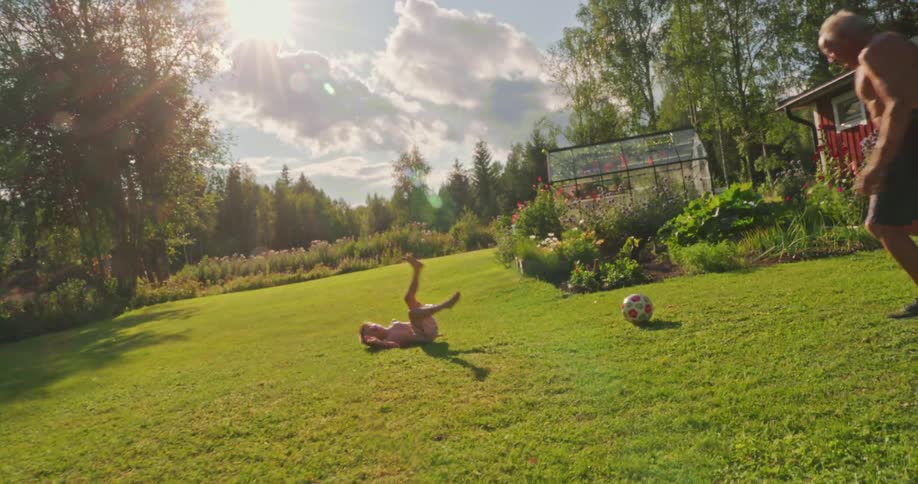 Grandfather playing ball in the backyard with his little grandson