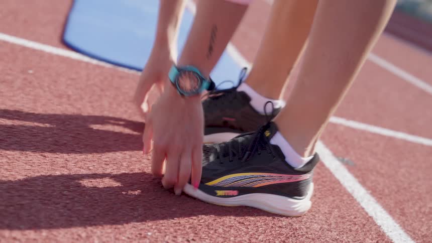 Close up of a womans legs jumping on an athletics track wearing black puma sneakers