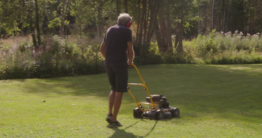 Man mowing grass in a yard surrounded by trees