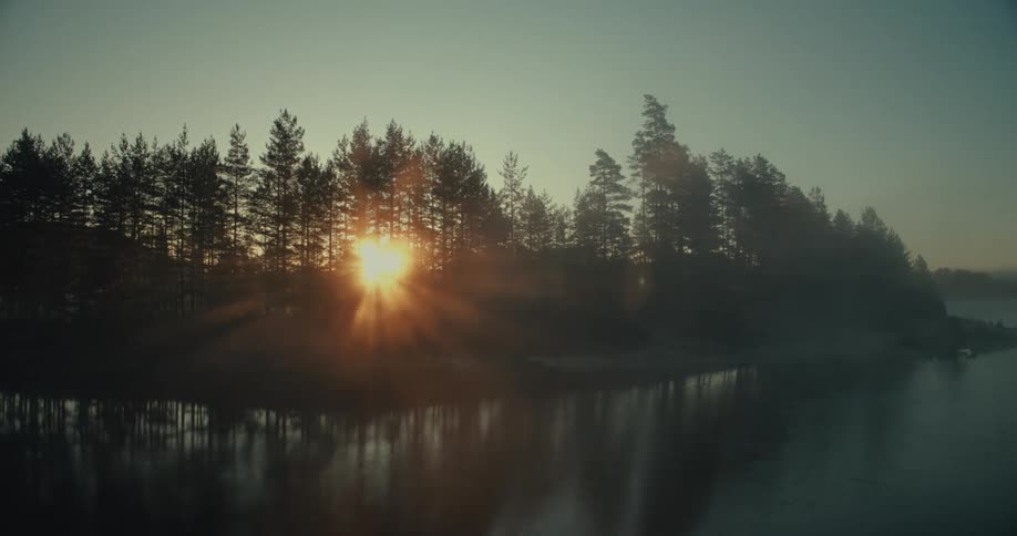 A river is lined with pine trees casting their reflections into the water