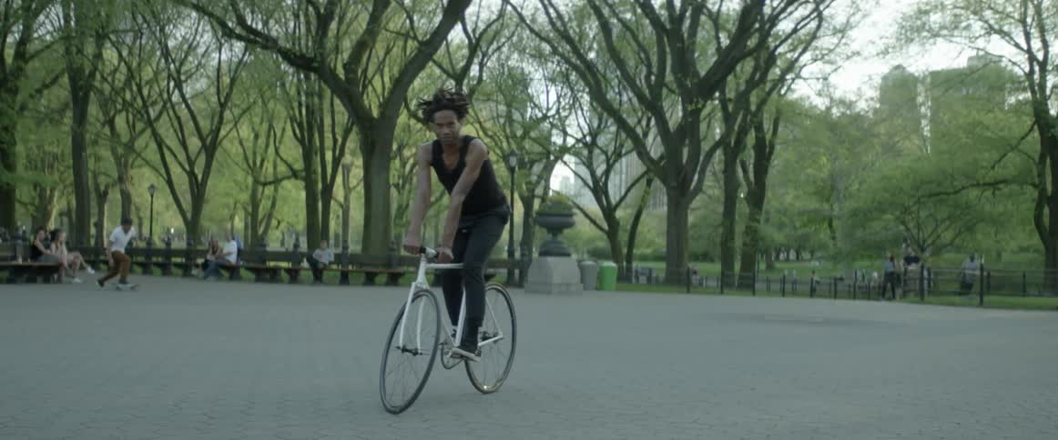 A person on a bike in a large city park in the day time