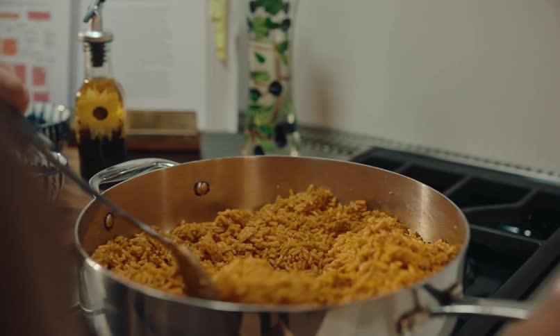 A woman is cooking something in a pan and putting a seasoning on top