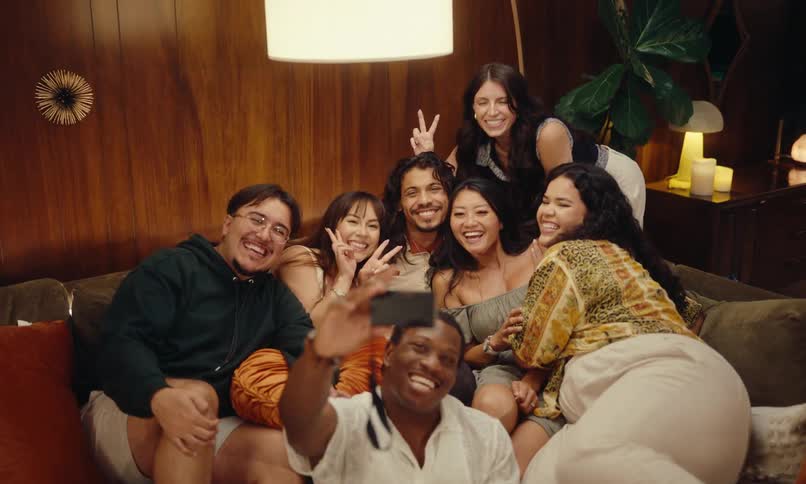 A group of friends gathering together sitting on a couch to take a selfie photo
