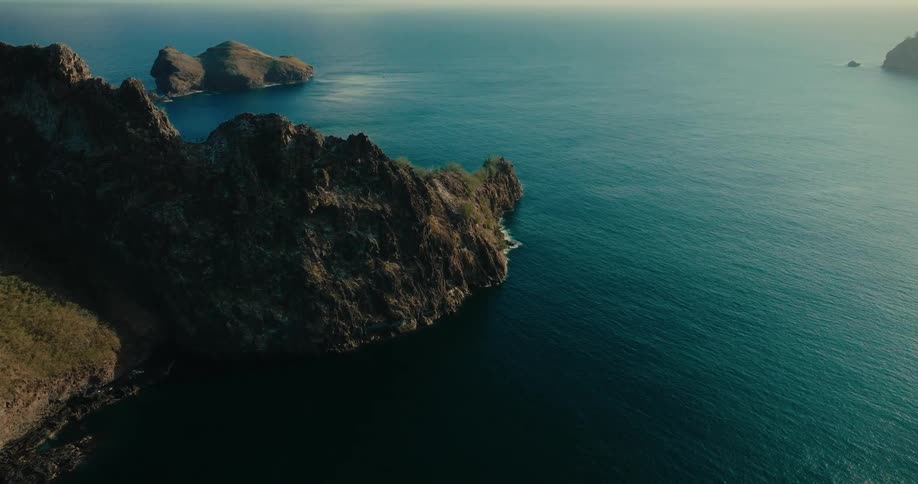 Wind waves flow past sloping coasts under a cloudy sky
