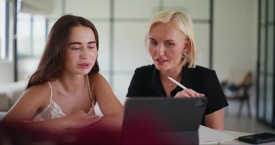 Two women sitting talking and using an ipad