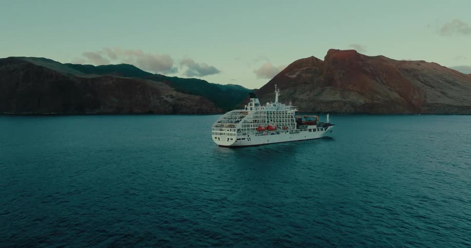 Cruise ship carrying containers at sea with mountains in the background