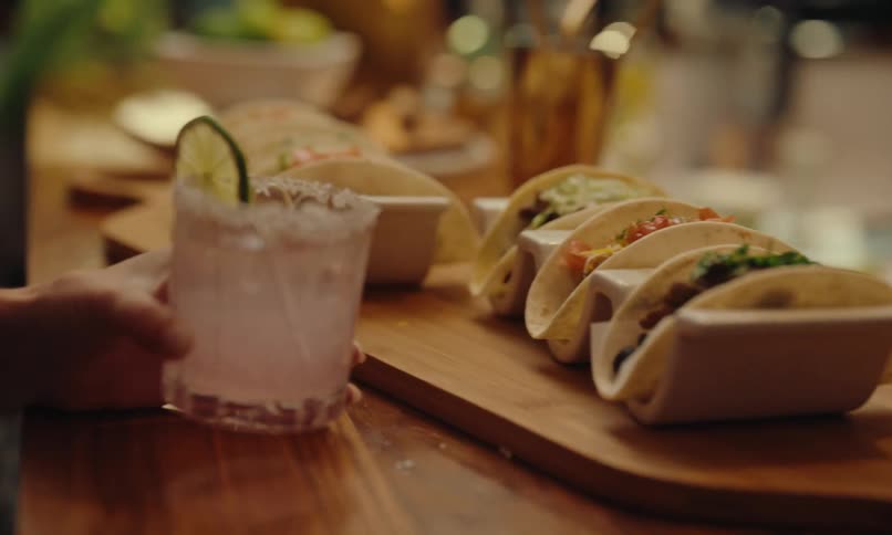 A person is having a drink and tacos