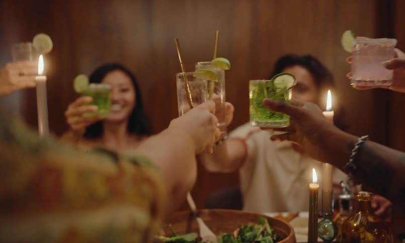 Friends sitting at a dinner table with food and toasting each other to the celebration