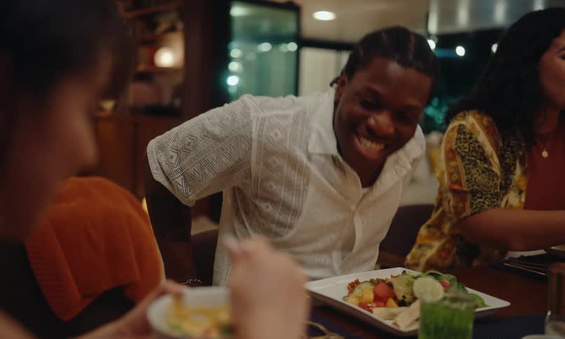 Friends sitting at a table serving themselves and chatting in a happy celebration