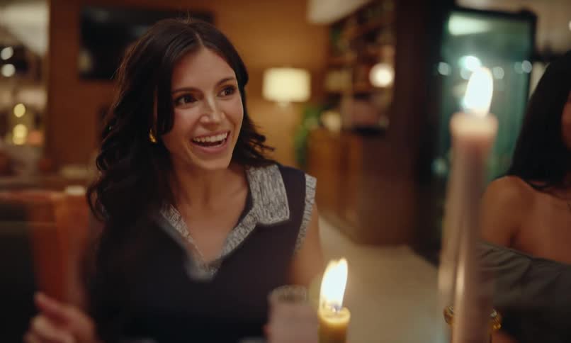 A woman is sitting and talking to people around her and she is smiling