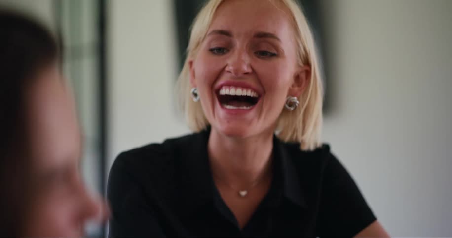 Woman laughing out loud while sitting next to her friend
