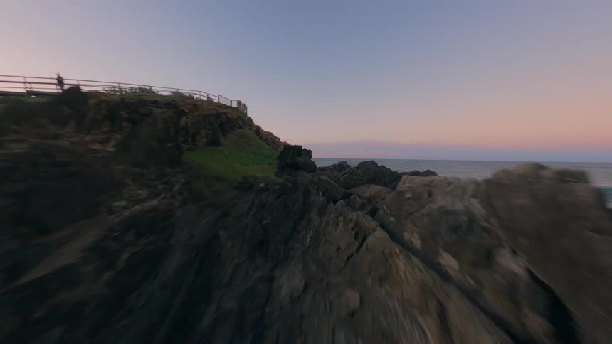 Aerial view of a steep rocky coastline reaching into the greenish waters of the sea at dawn