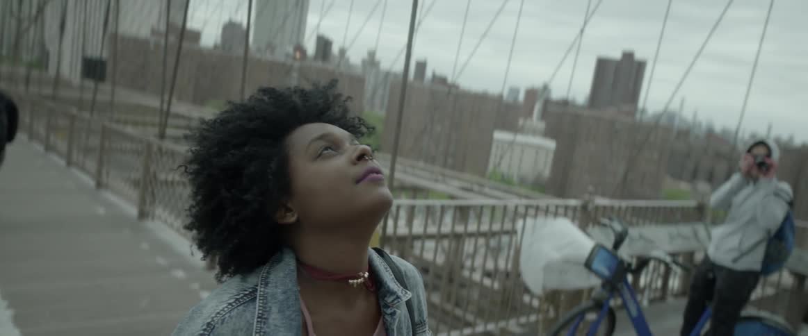 A young lady is looking up on a bridge