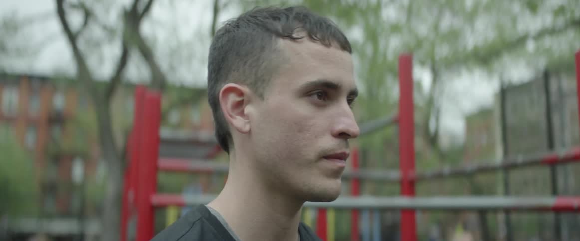 A man sits outside of a playground