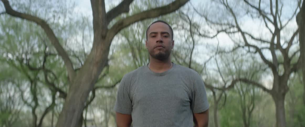 A man stands outside under trees