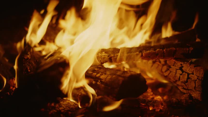 A campfire burns brightly outdoors at night
