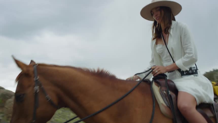 A man and a woman riding two horses and they are wearing hats