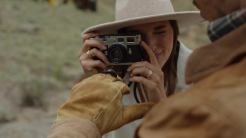 Woman with a vintage camera photographing a beetle on a mans gloved hand