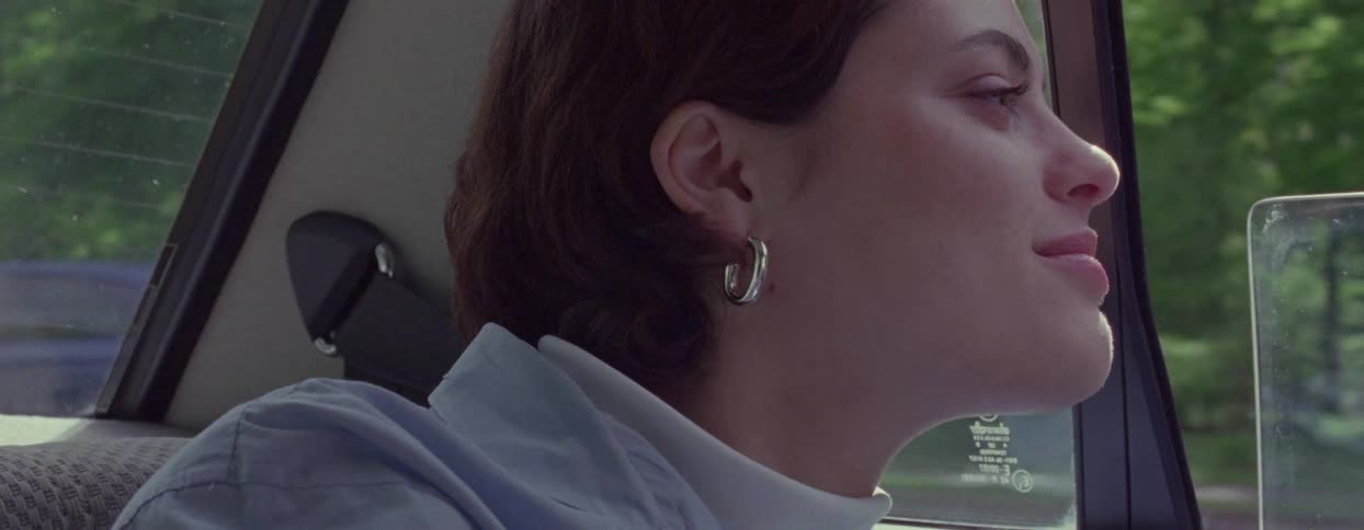 A woman rests in the back of the moving car