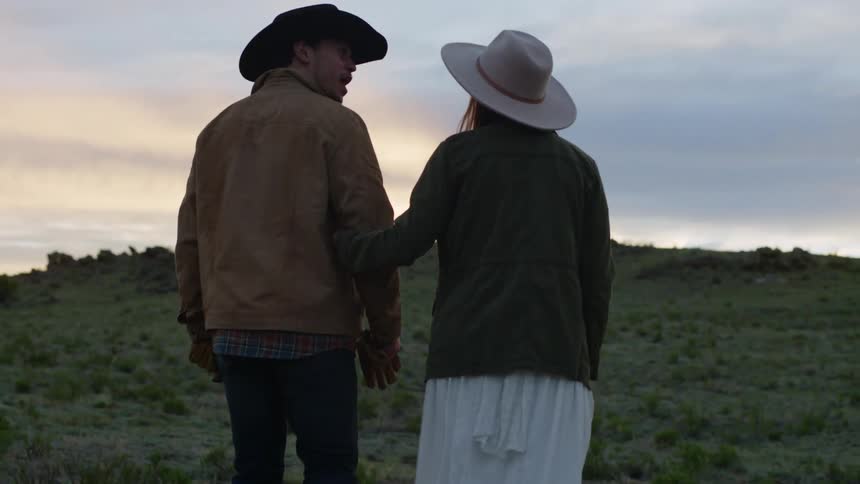 Rear view of a couple walking through a mountain valley on a cloudy late afternoon