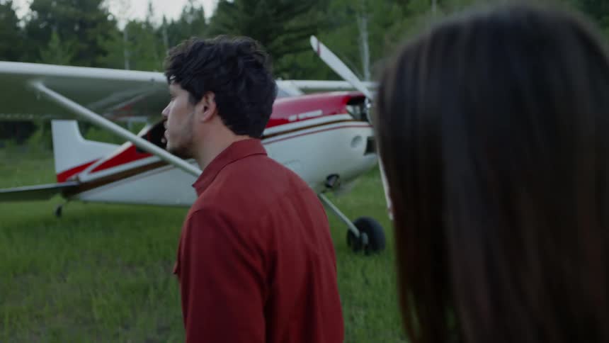 Woman and man walking side by side in a natural setting with a private plane next to them