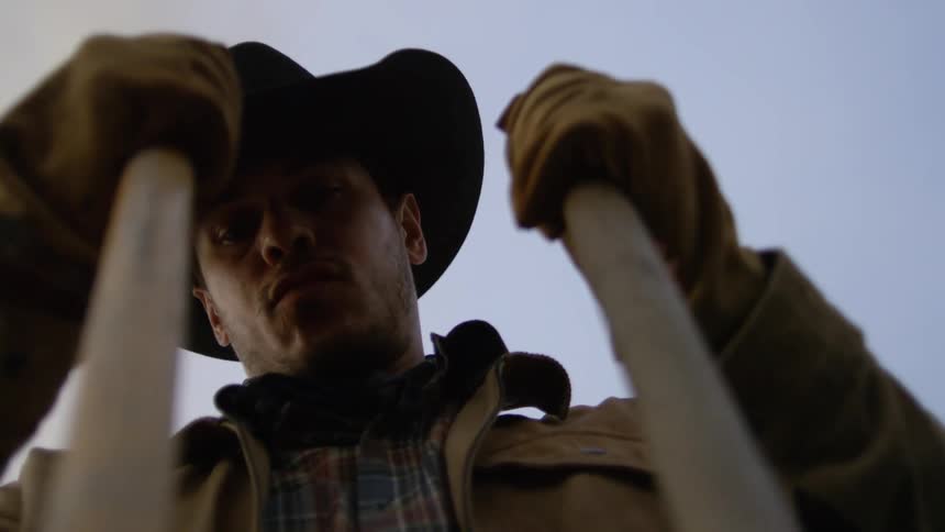 Male rancher uses a post digger on an overcast day