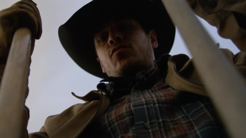 Cowboy holding two thin wooden stakes