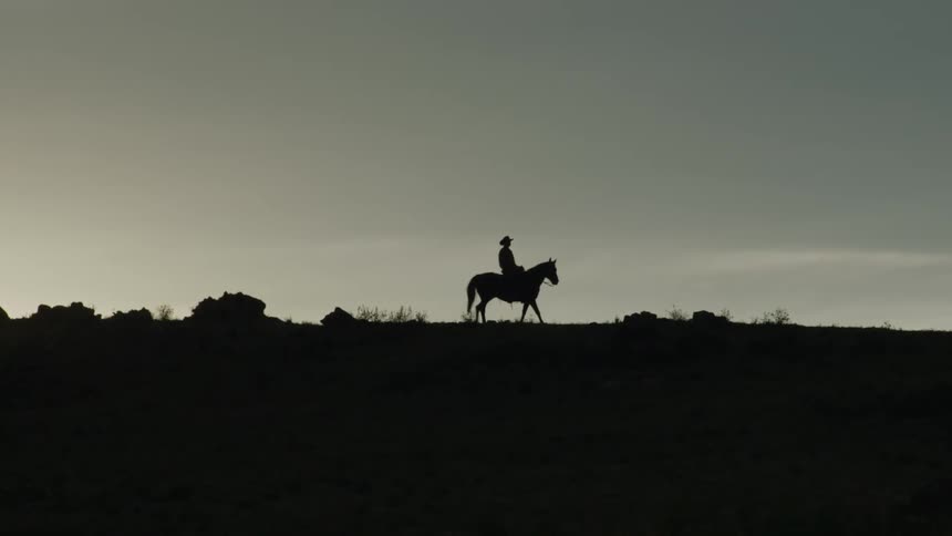 Silhouette of a man on a hill riding a horse