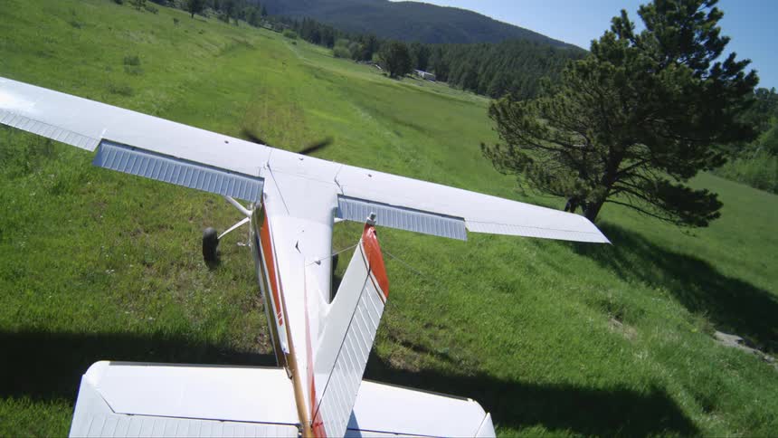 A small propeller plane landing on a grass runway