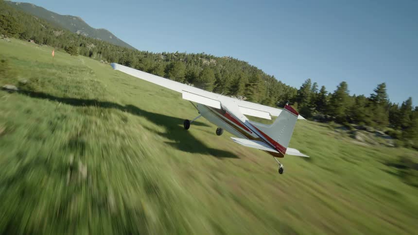 A private plane lands in a valley in a remote forested area on a sunny day