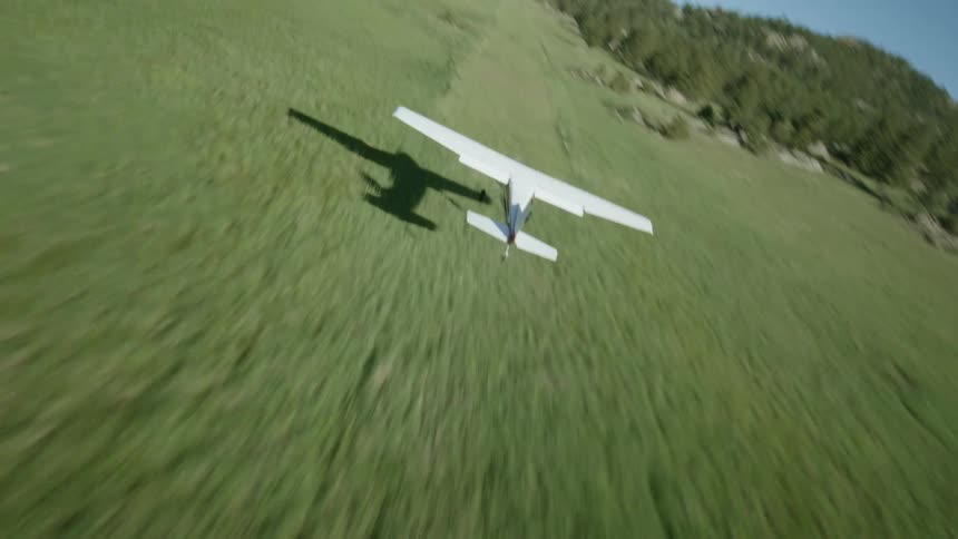 Small private plane posing in an environment with grass and trees and mountains around