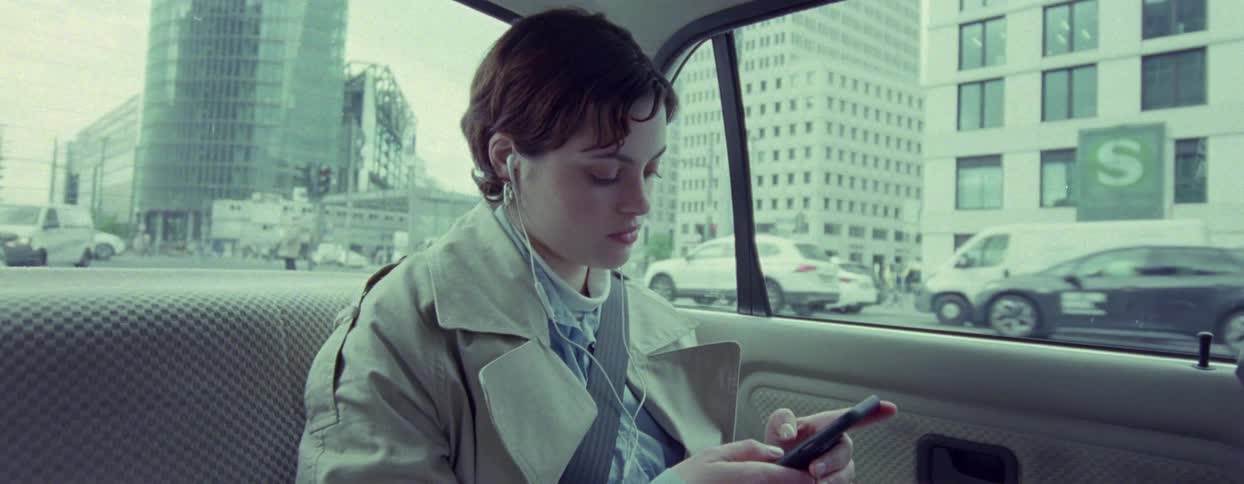 Female passenger in the rear seat interacts with her smartphone during a trip through the city