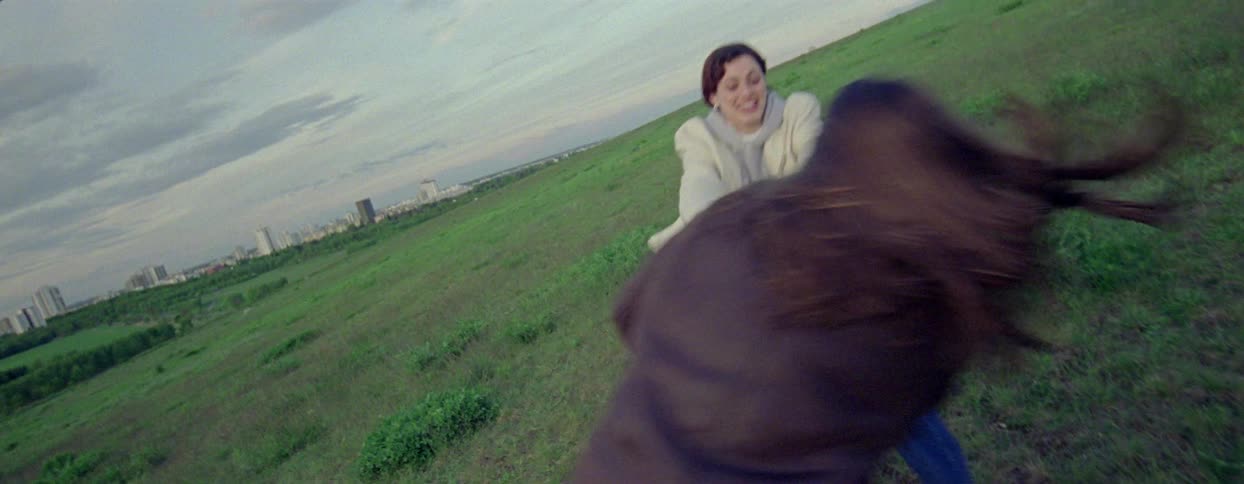 Two young women holding hands spinning and playing in a field
